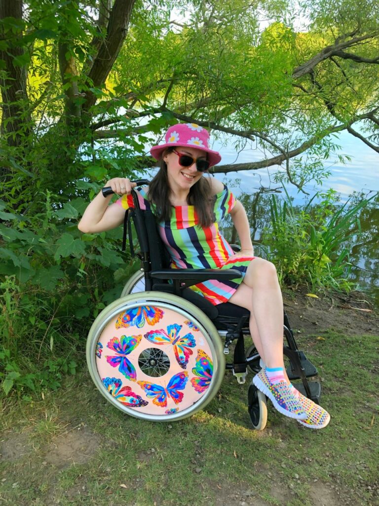 Rebecca, a white woman with long brown hair, sits in her wheelchair
